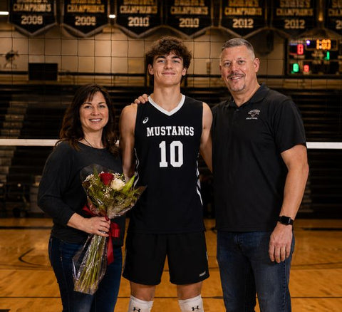 Boys volleyball senior night gifts — senior player at the net with parents on senior night