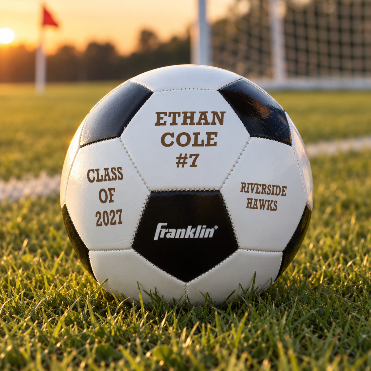 Personalized soccer ball engraved with a player name and #7, Class of 2027 and a team name, resting on a field at sunset, a senior night soccer gift