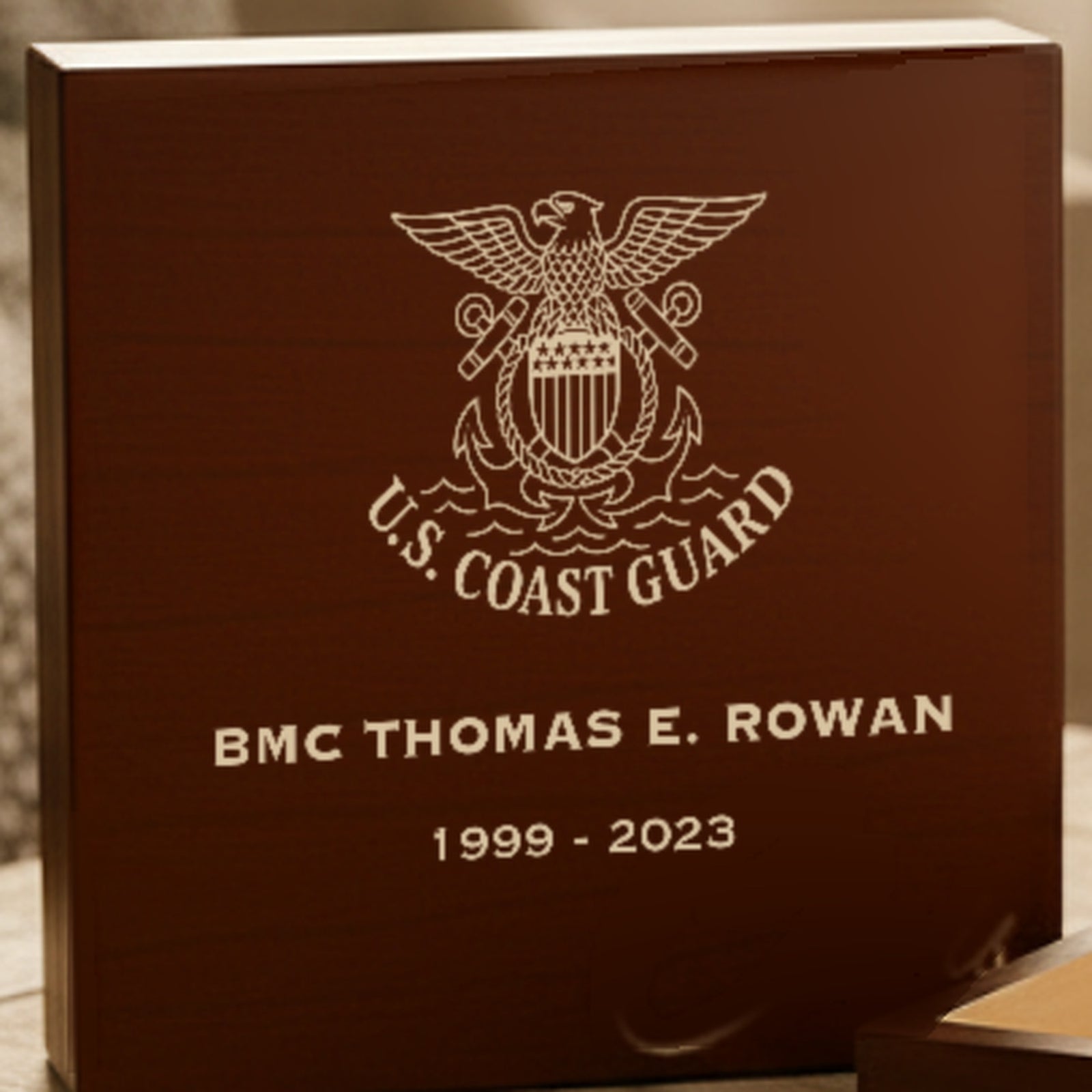 Close view of the U.S. Coast Guard crest laser engraved on the cherry lid of the wooden keepsake box with rank, name and years.