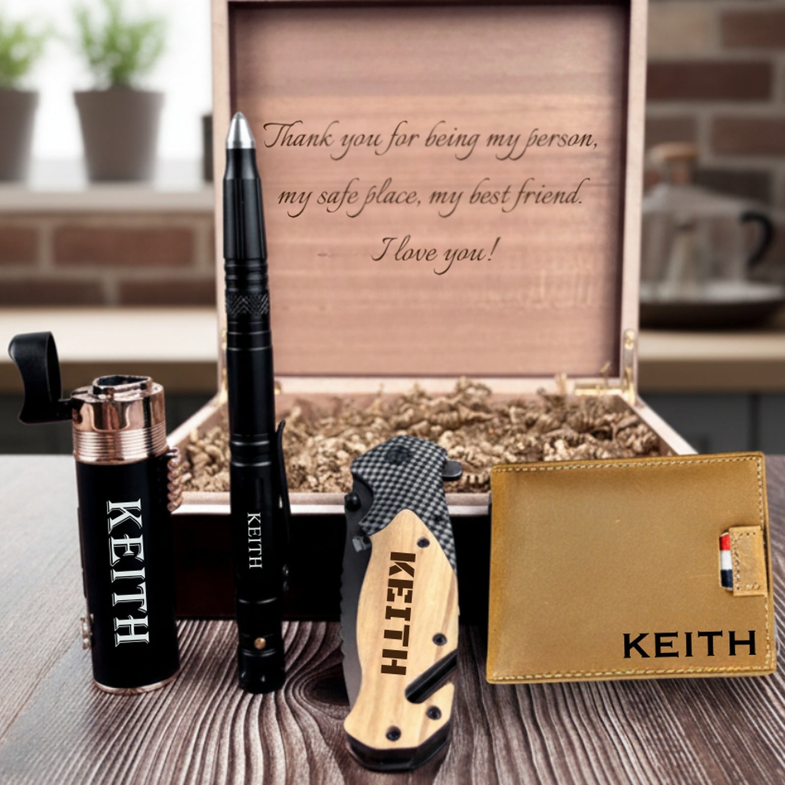 Personalized gift set for men with the name KEITH engraved on a triple torch lighter, tactical pen, folding knife and leather wallet beside an open wooden box with a message inside
