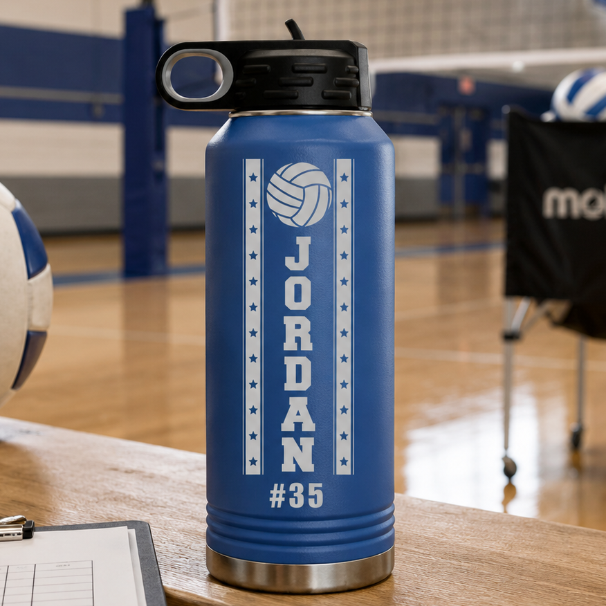 Blue insulated water bottle with black lid engraved with volleyball icon, sample name "JORDAN" and number "#35" surrounded by stars, displayed on gym floor.