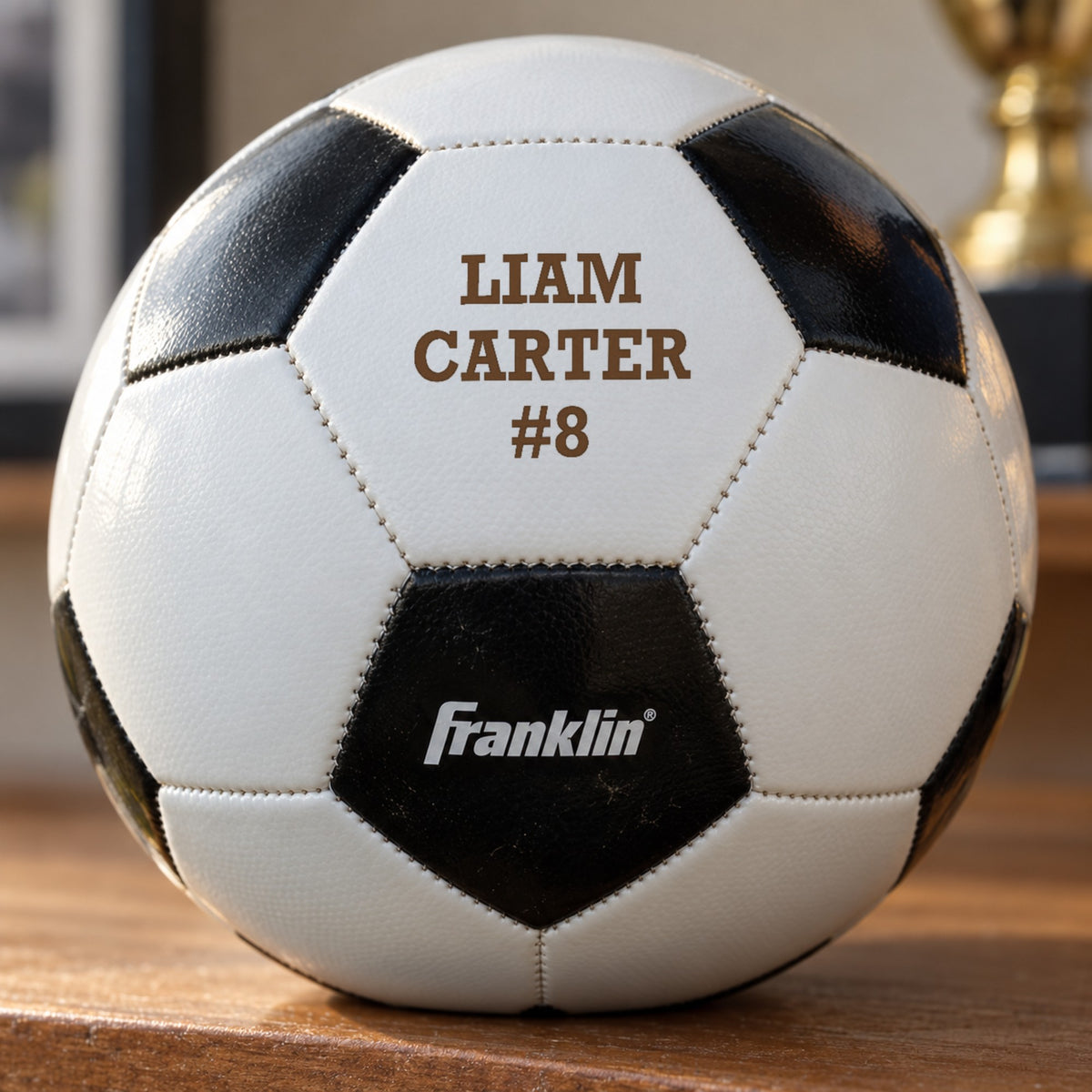 Close-up of a soccer ball panel laser engraved in warm brown with the name Liam Carter and number 8, a personalized senior soccer gift
