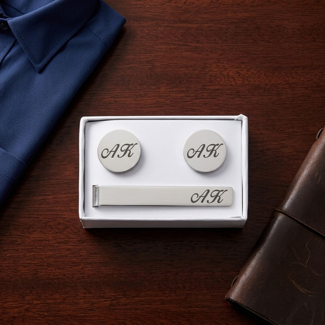 Three-piece cufflinks and tie bar set with sample monogram "AK" engraved on round cufflinks and rectangular bar, displayed in white gift box packaging.