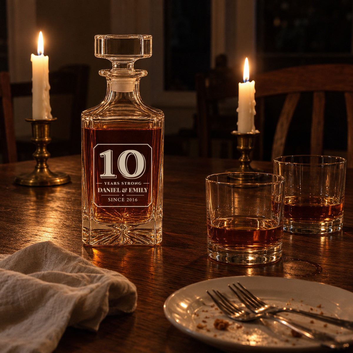 Personalized decanter engraved 10 Years Strong, Daniel & Emily, on a candlelit dinner table with two glasses, a 10th anniversary gift for him