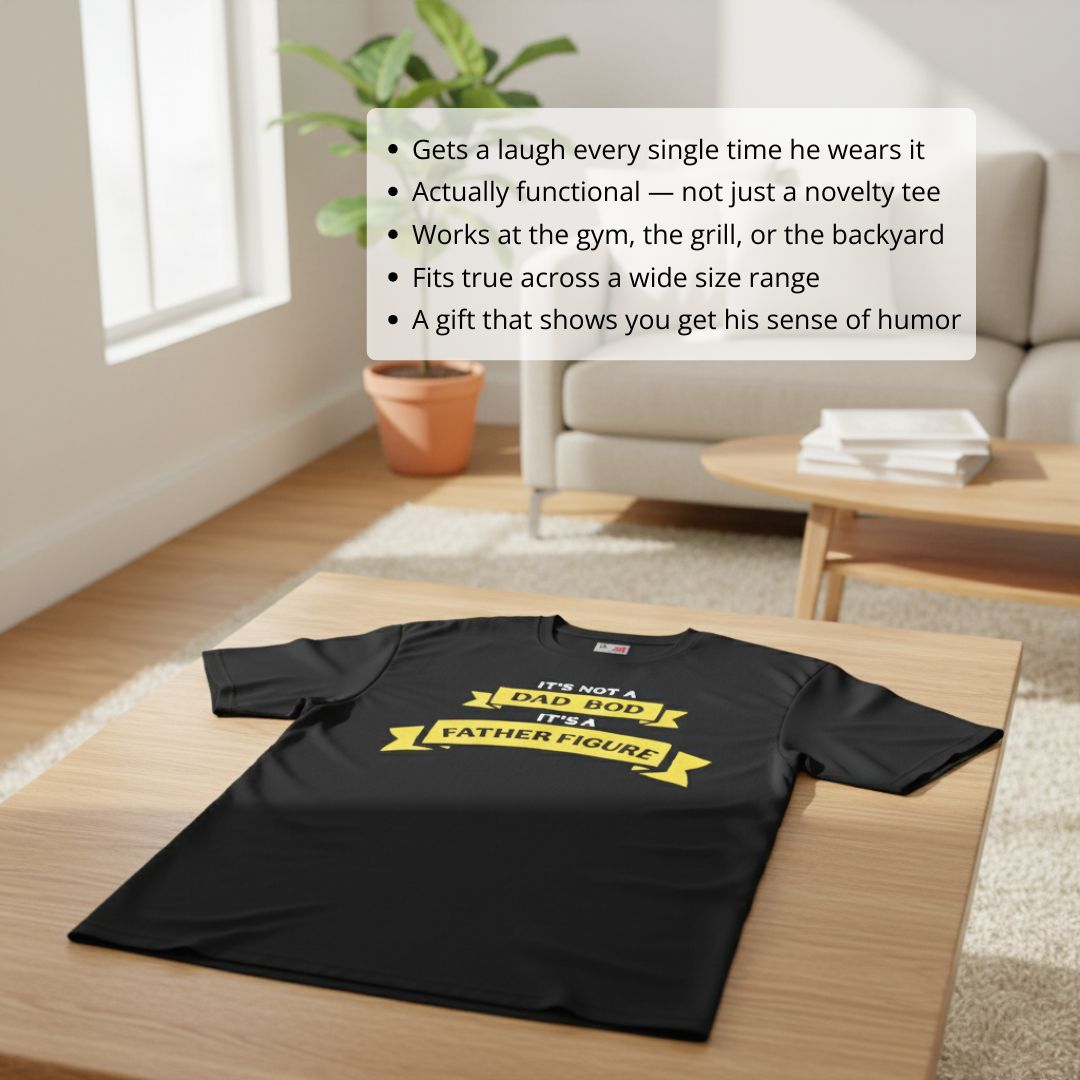 Black t-shirt with yellow banner text reading "It's not a dad bod, it's a father figure" laid flat on wooden table in home setting