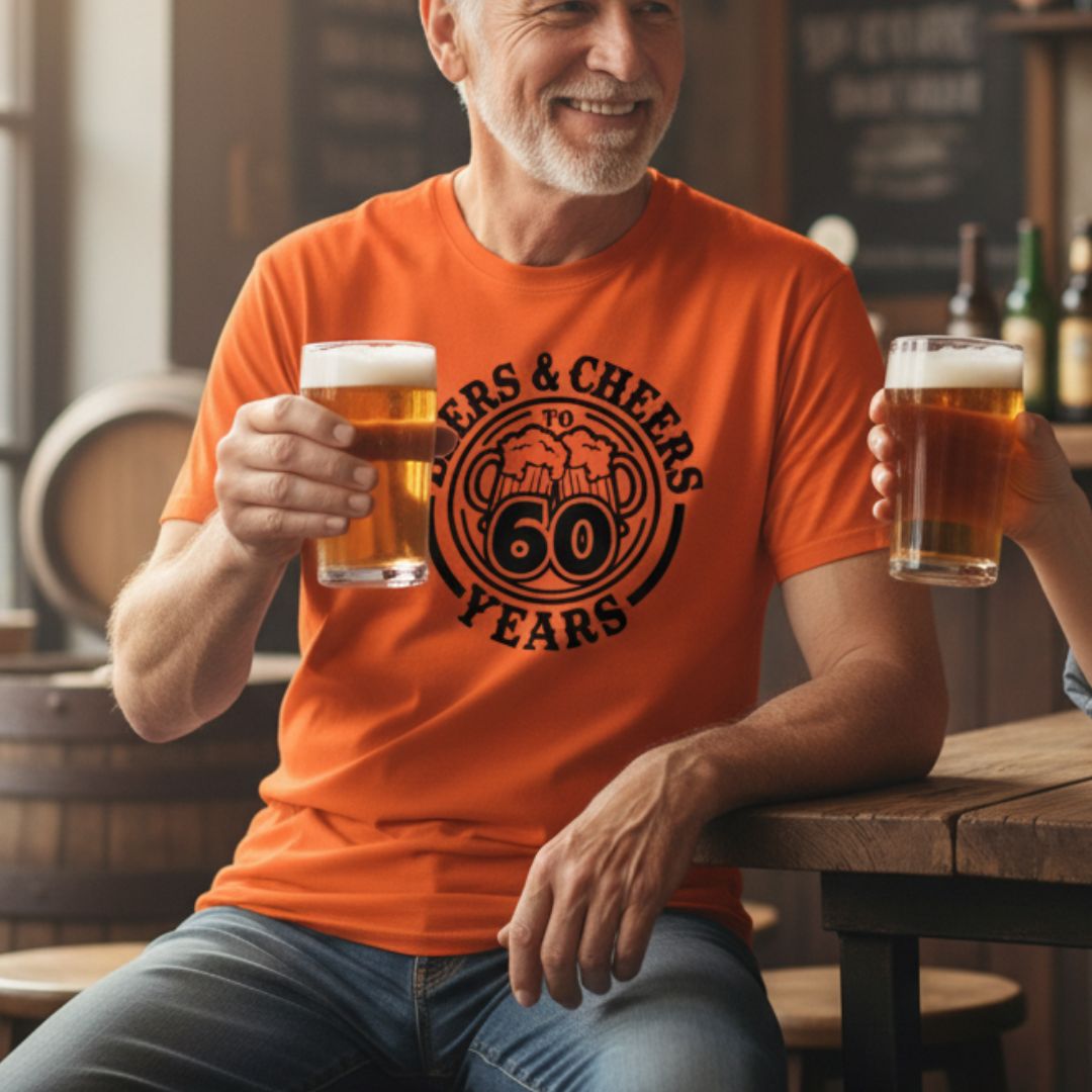 Orange t-shirt with "Beers & Cheers to 60 Years" design and circular badge graphic in black, worn by man holding two beer glasses