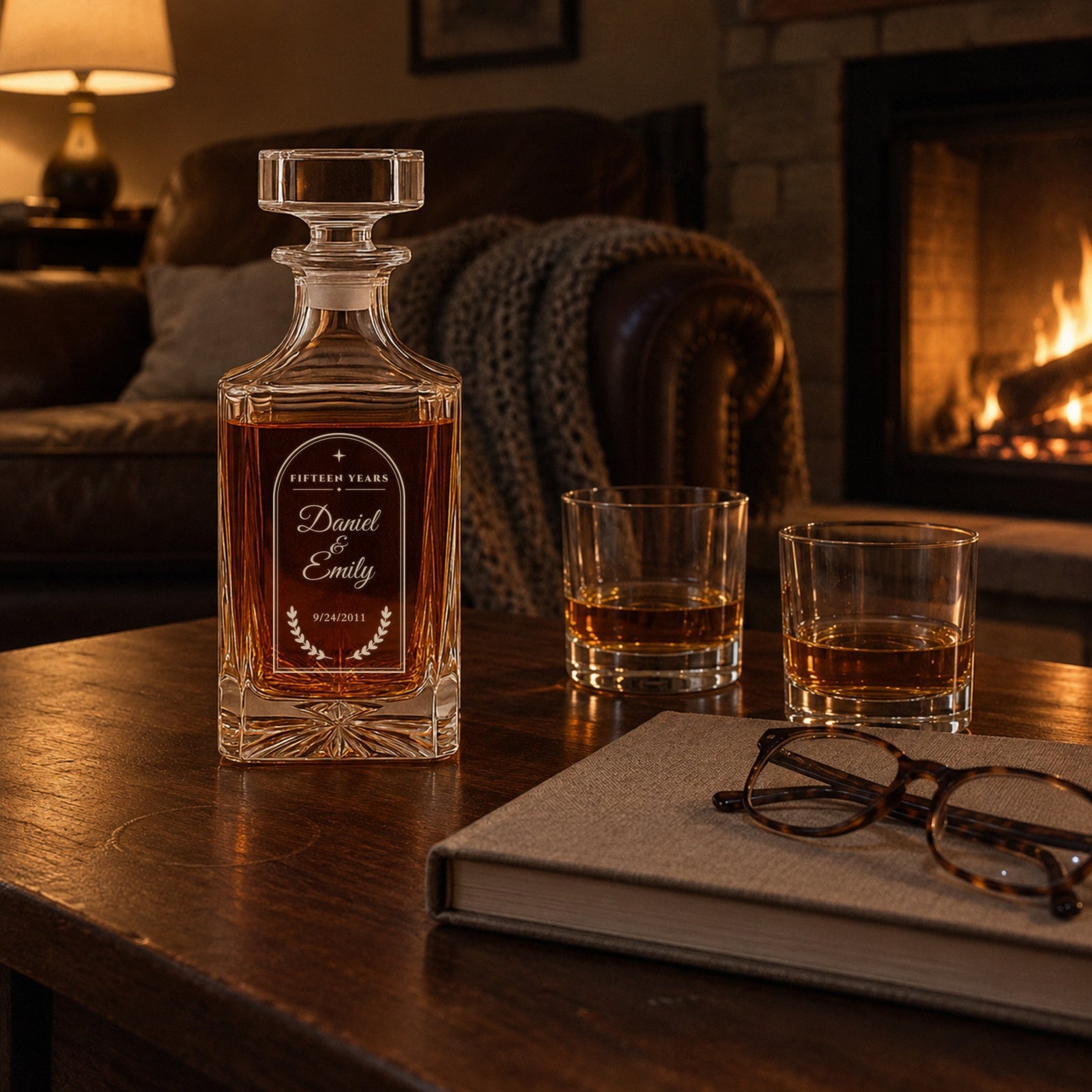 Engraved 15 year anniversary decanter with names Daniel and Emily on a living room table by the fireplace, two glasses of bourbon poured beside it