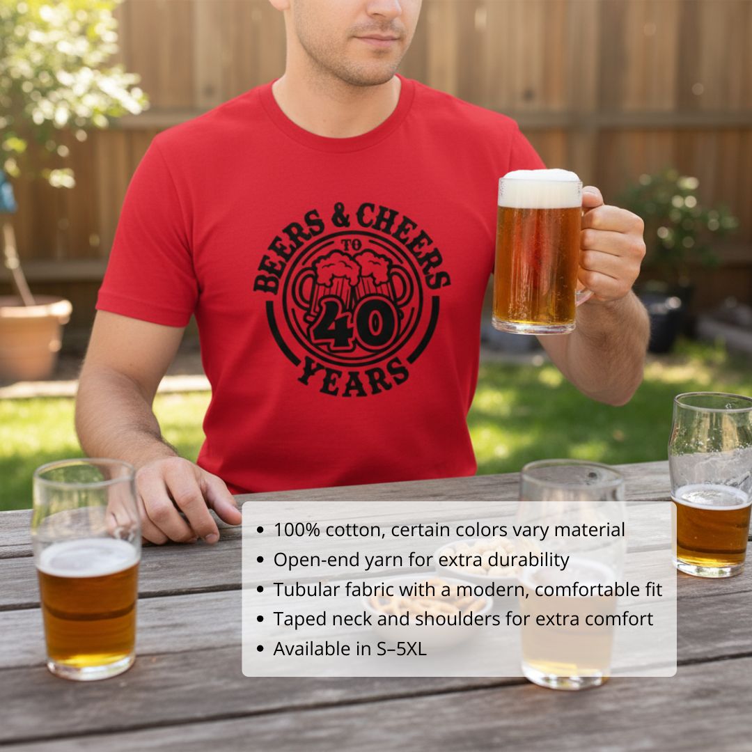 Man wearing red cotton t-shirt with black "Beers & Cheers to 40 Years" design and beer mug, seated outdoors at wooden table