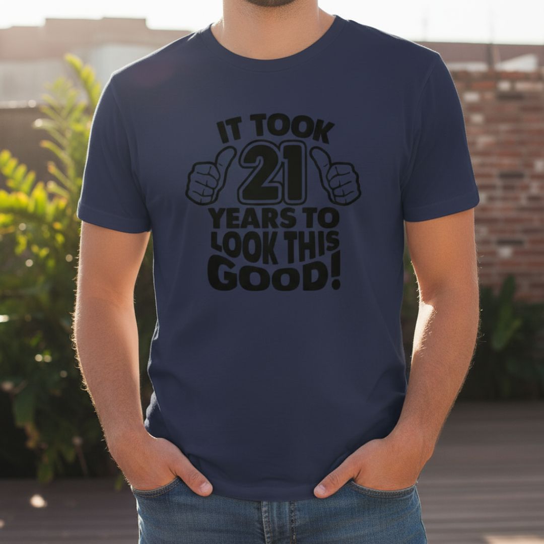 Navy t-shirt printed with "It Took 21 Years to Look This Good!" text and thumbs-up graphics in black ink, worn outdoors.