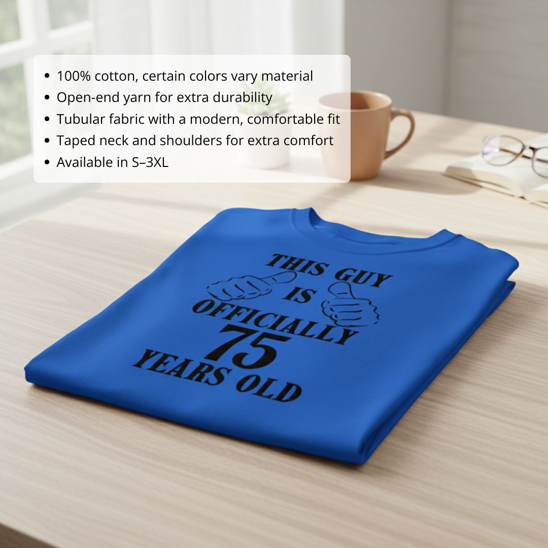 Royal blue t-shirt printed with "This Guy is Officially 75 Years Old" text and thumbs-up graphics, folded on wooden surface