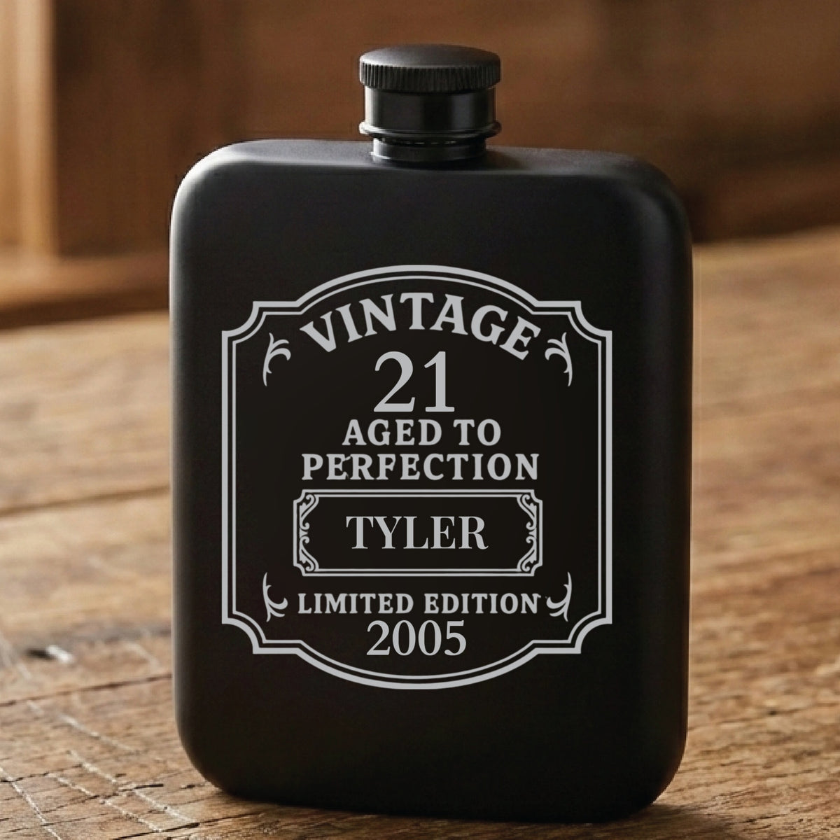 Matte black personalized 21st birthday flask laser engraved with a vintage Aged to Perfection label reading 21, the name Tyler and the birth year 2005.