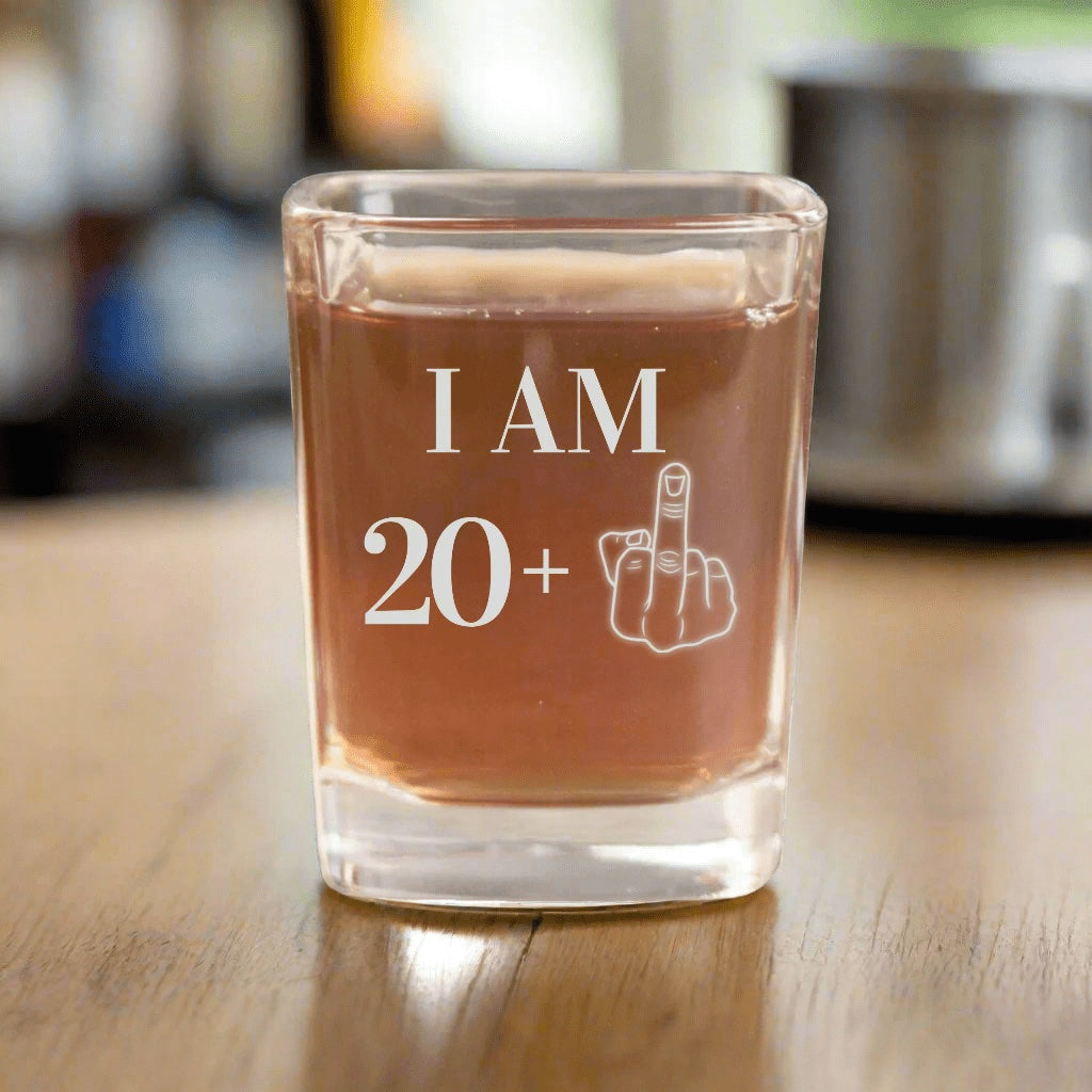 The original 21st birthday shot glass photo: I AM 20 plus a middle finger engraved on a square glass, a funny 21st birthday gift