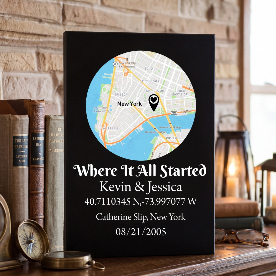 Black leatherette sign displaying customized map of New York with sample text "Where It All Started," names "Kevin &amp; Jessica," coordinates, location "Catherine Slip, New York," and date "08/21/2005