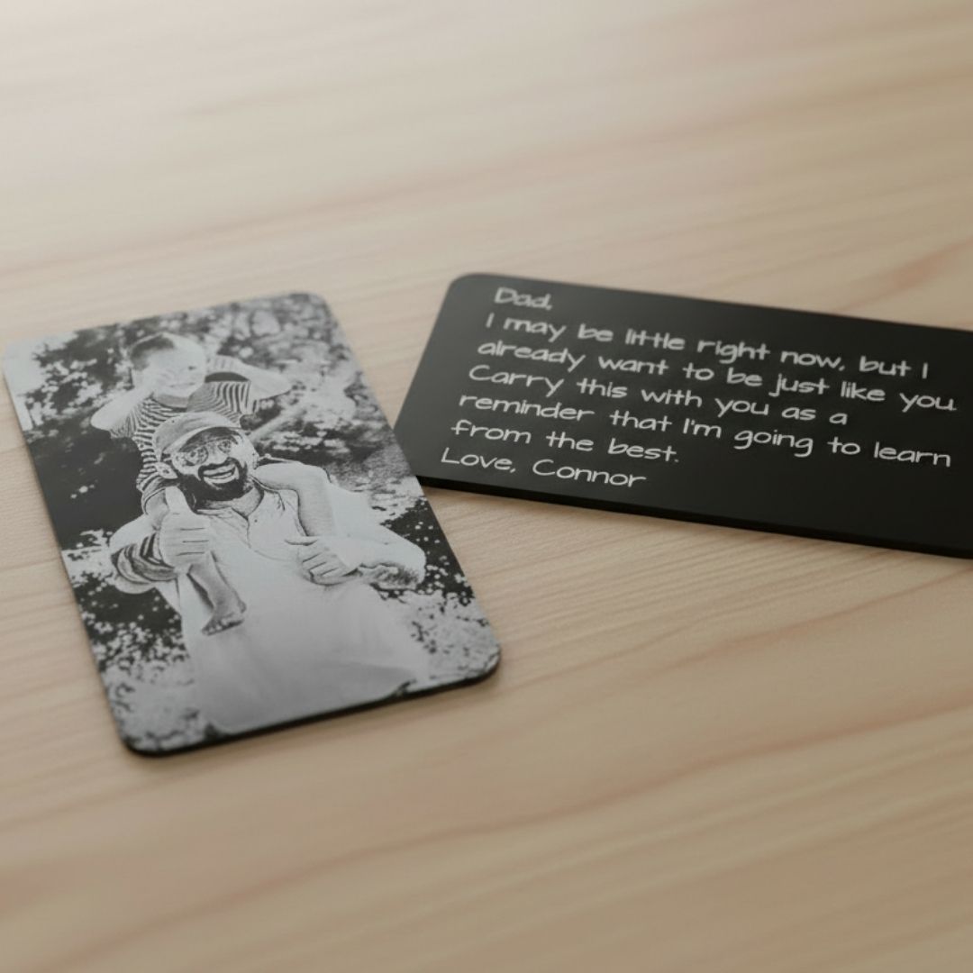 Black anodized aluminum wallet card with laser-engraved photo on front and personalized message sample reading "Dad, I may be little right now..." on back.