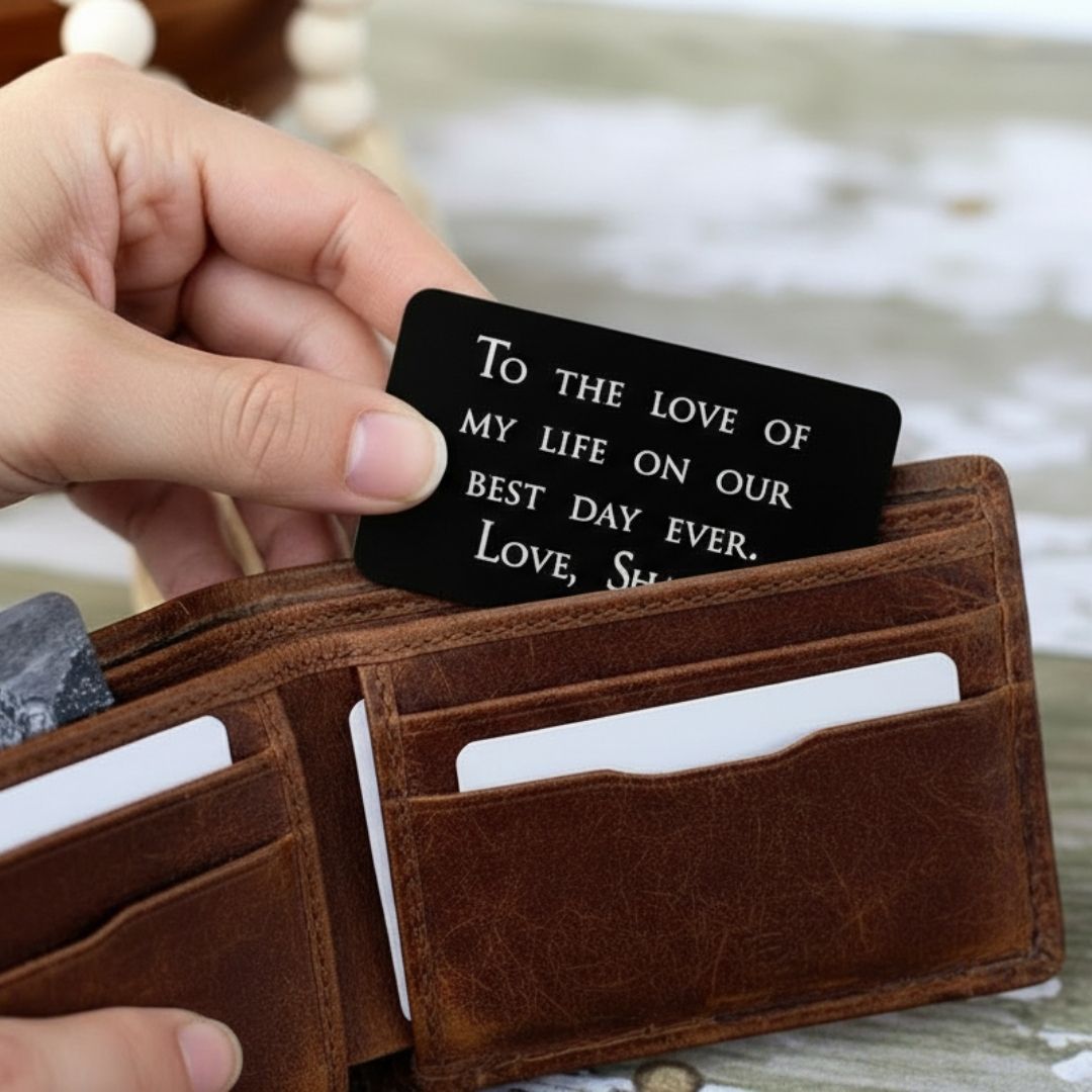 Black anodized aluminum wallet insert card with sample engraving reading "To the love of my life on our best day ever. Love, She" displayed in brown leather wallet.
