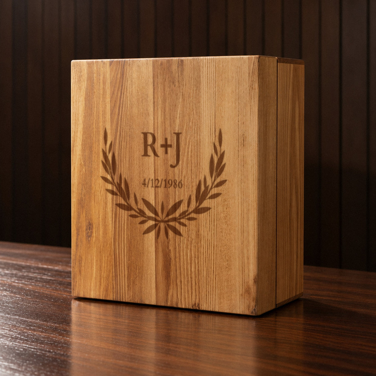Closed pine chest of the 40th anniversary gift for husband decanter set, engraved on the front with a laurel wreath, initials R+J and the 4/12/1986 wedding date