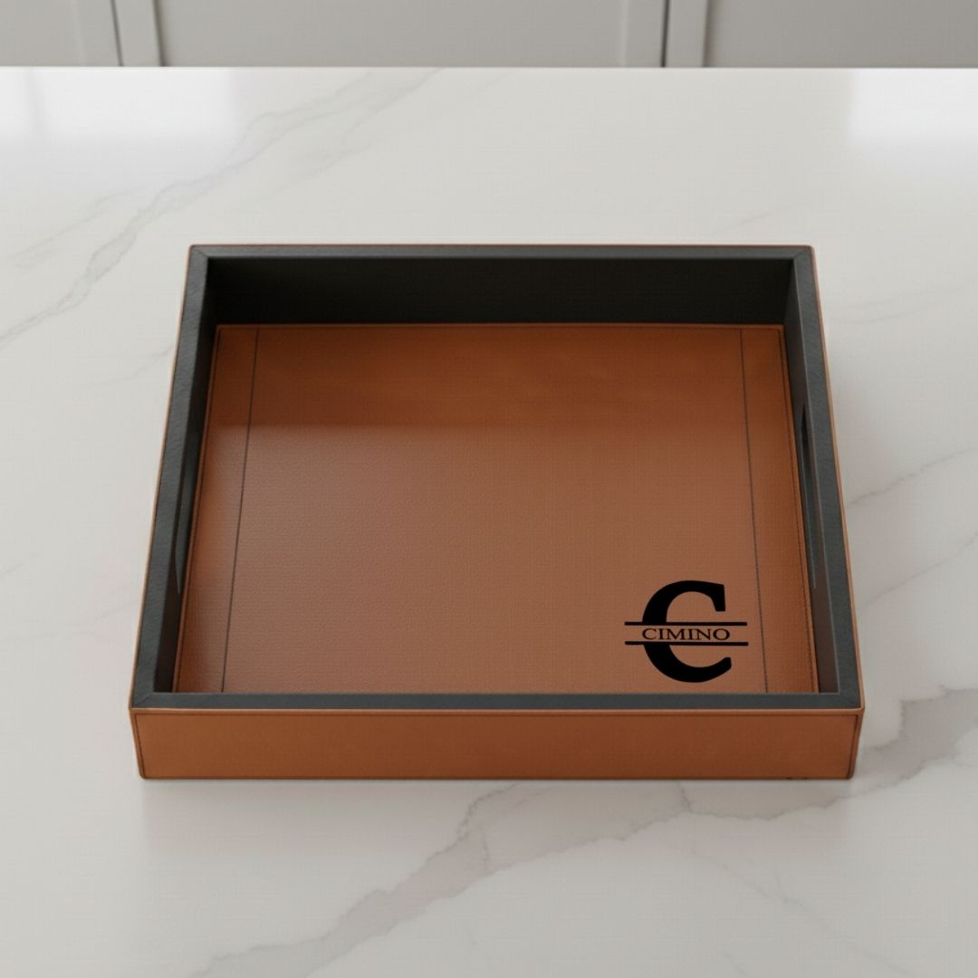 Tan leatherette serving tray with raised walls and black engraved CIMINO logo sample on front, shown open from above on marble surface