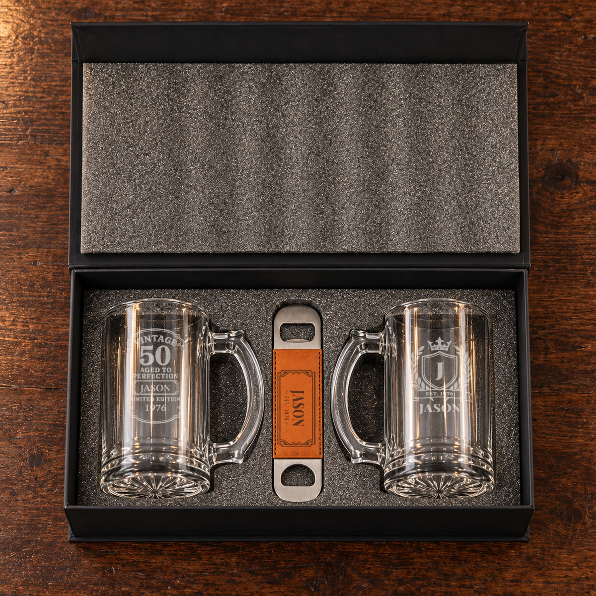 The 50th birthday beer gift set open in its foam-lined box: a Vintage 50 mug and a crest mug for Jason, with his engraved bottle opener