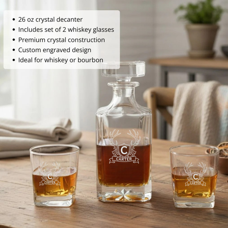 Engraved whiskey decanter filled with bourbon between two matching antler crest glasses on a rustic wooden table, with a feature list