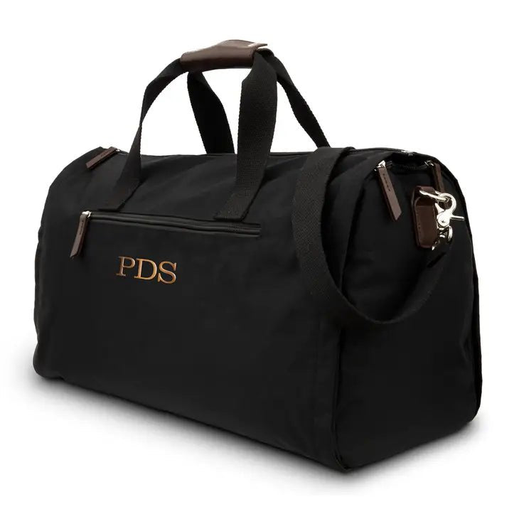 Black convertible garment duffel bag with the initials PDS embroidered in copper thread on the front, brown handle wraps and a shoulder strap, a custom garment bag