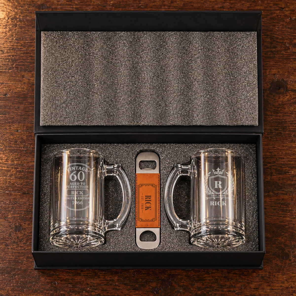 The 60th birthday beer gift set open in its foam-lined box: a Vintage 60 mug and a crest mug for Rick, with his engraved bottle opener