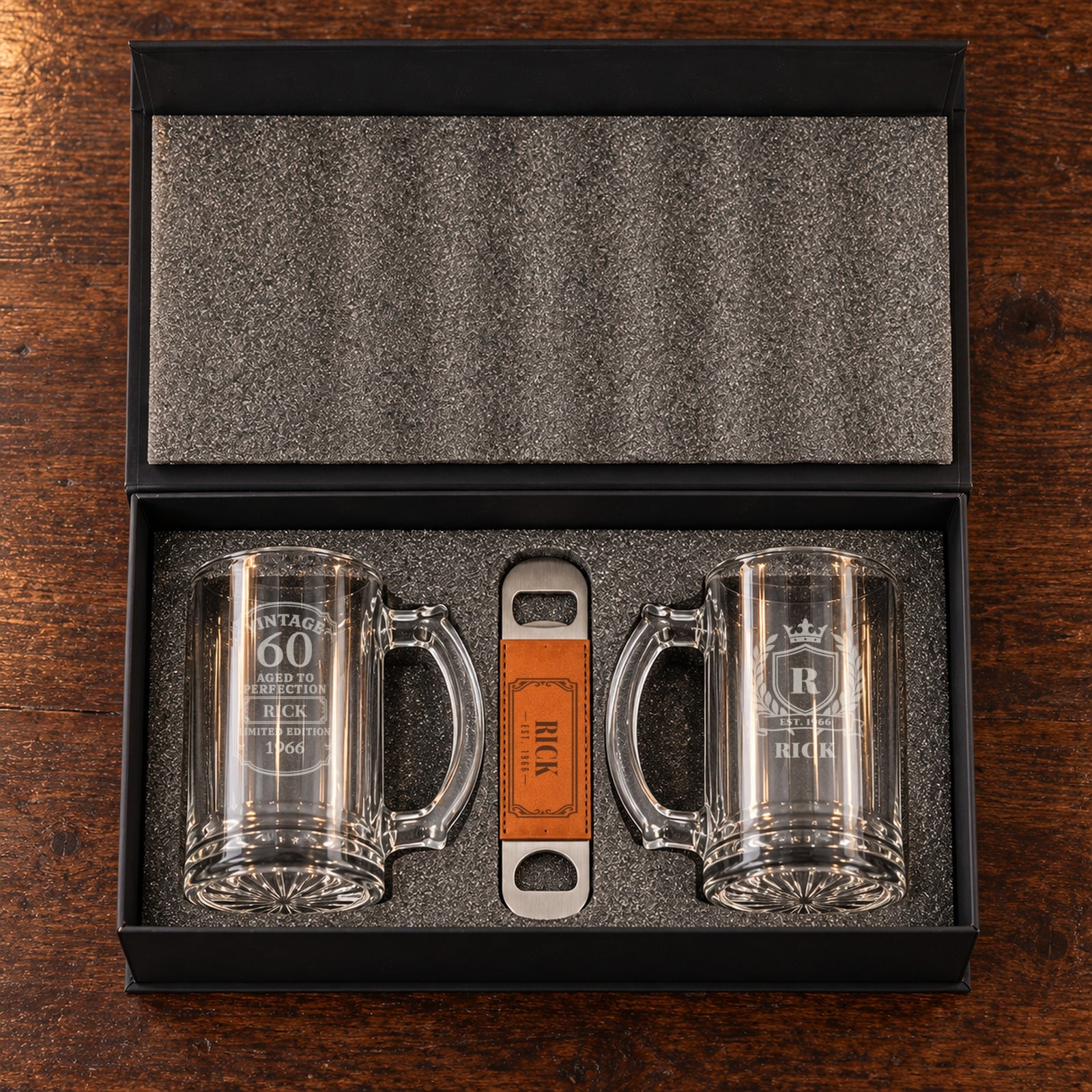 The 60th birthday beer gift set open in its foam-lined box: a Vintage 60 mug and a crest mug for Rick, with his engraved bottle opener
