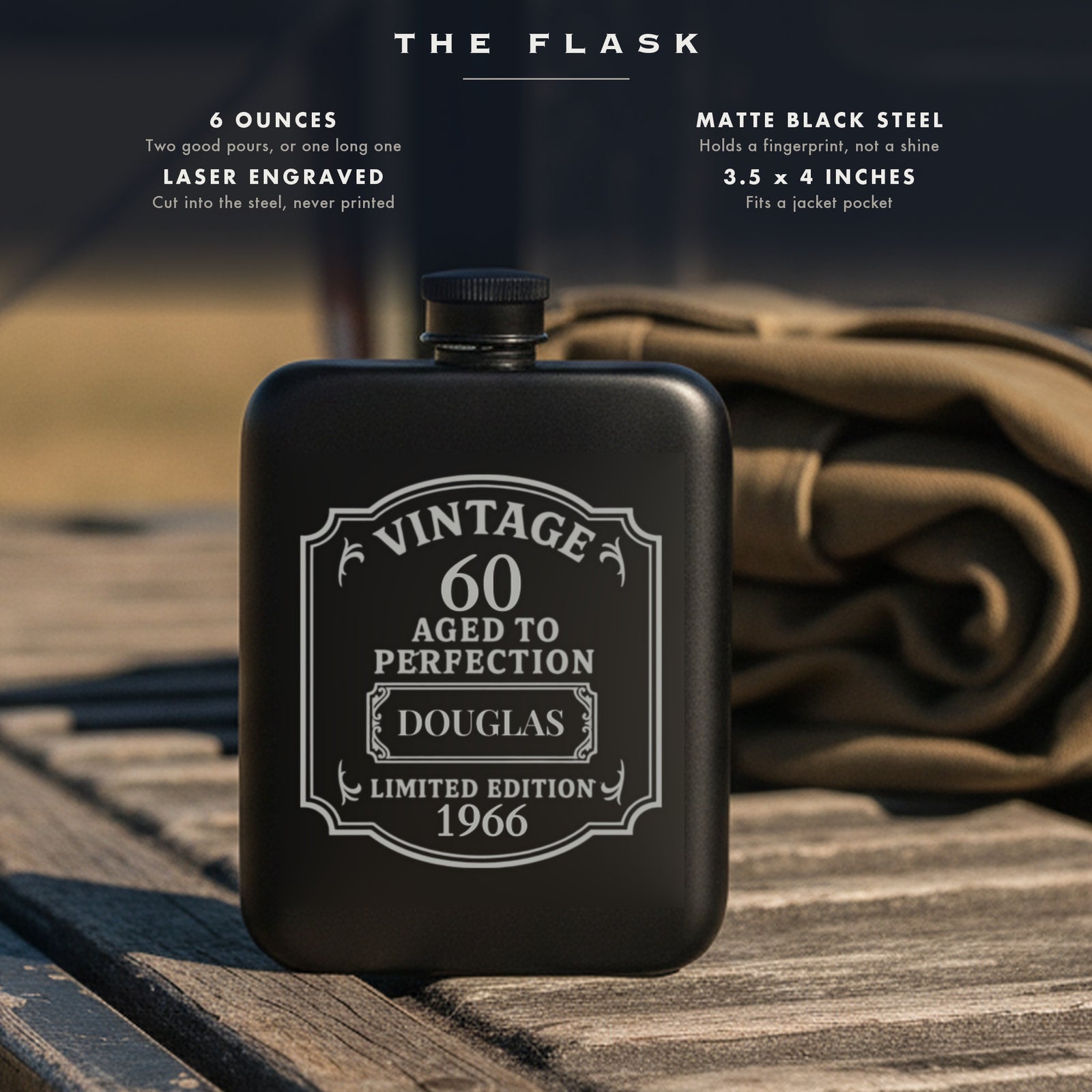 Specifications for the vintage 60th birthday flask, 6 ounces, matte black steel, laser engraved, 3.5 by 4 inches, shown on a wooden truck tailgate in daylight.
