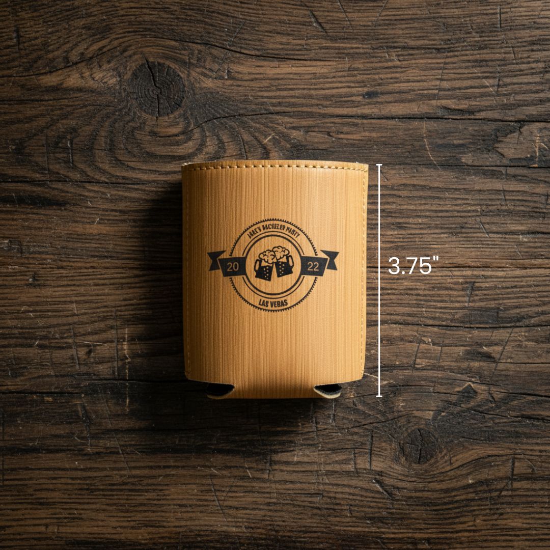Tan faux leather koozie with laser-engraved circular badge design featuring two beer mugs and sample text "LAST BACHELOR PARTY 2022 LAS VEGAS," measuring 3.75 inches tall, displayed on rustic wood surface.