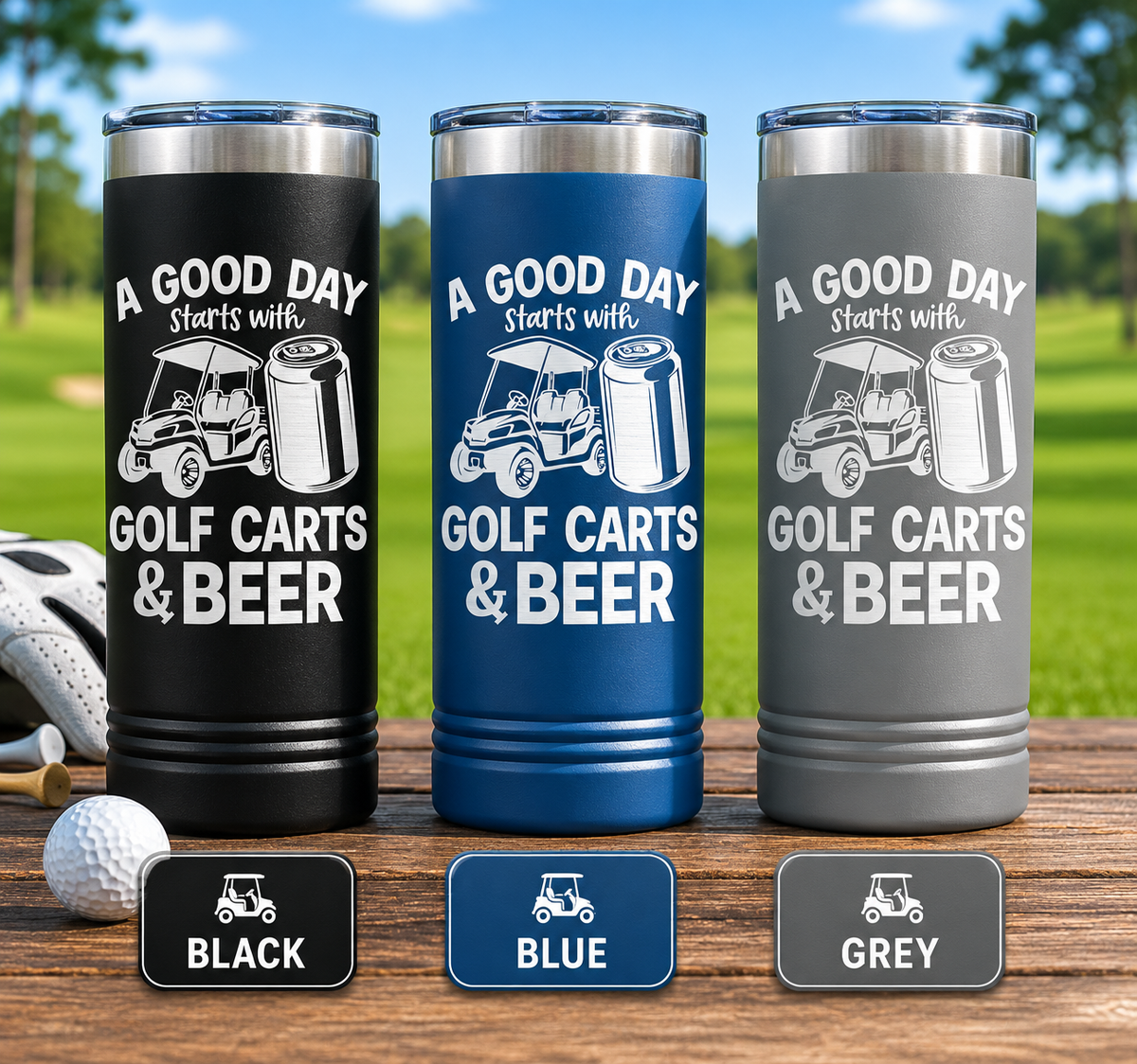 Three insulated tumblers in black, blue, and grey with "A Good Day Starts with Golf Carts & Beer" design and golf cart and beer can graphics, displayed outdoors on a wooden table with golf balls and a golf course background
