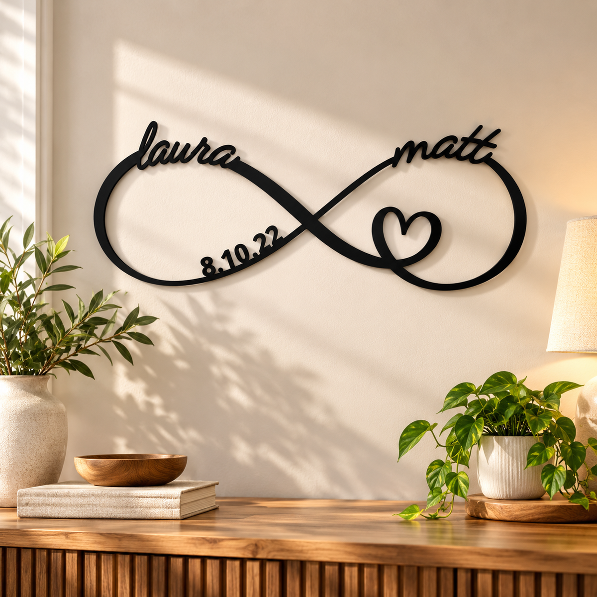 Black personalized infinity anniversary sign with the names laura and matt, a heart and the date 8.10.22, hanging above a wooden console table