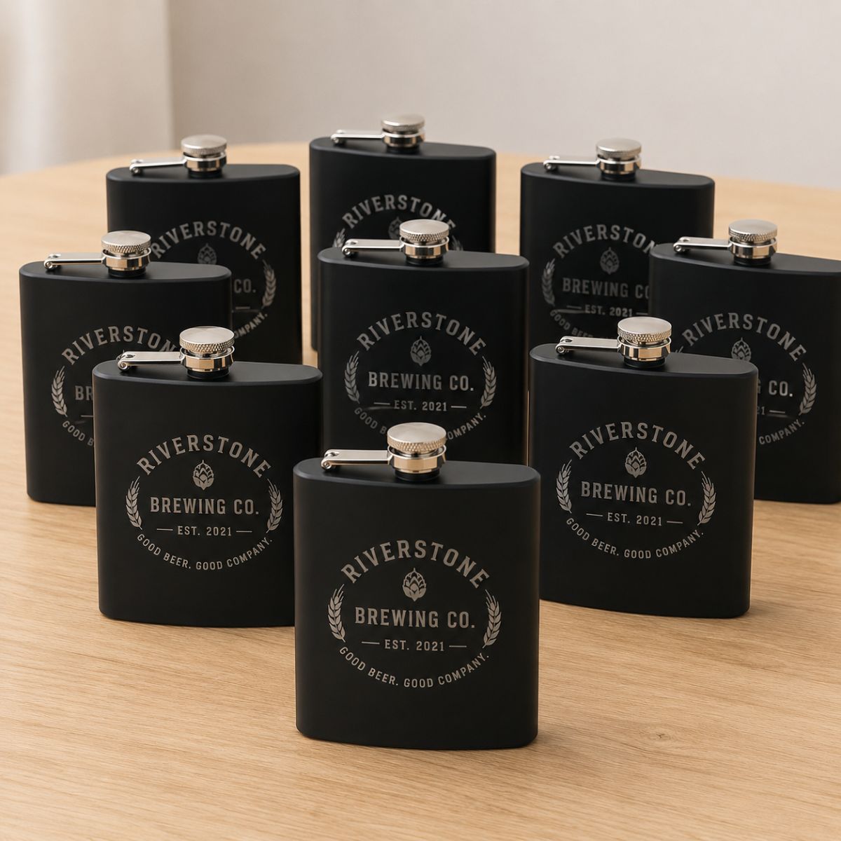 Black flasks with 'Riverstone Brewing Co.' branding on a wooden surface