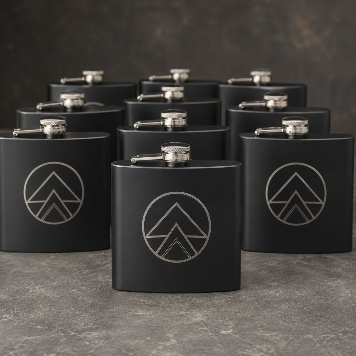 Group of matte custom logo flasks engraved with the same sample company logo, arranged together to show bulk corporate gift orders.