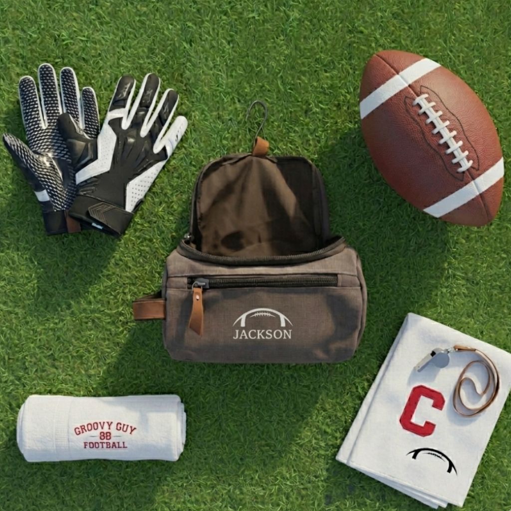 Washed canvas toiletry bag personalized with sample name "JACKSON" and football motif, displayed with football gloves, football, towel, and captain's armband on artificial turf