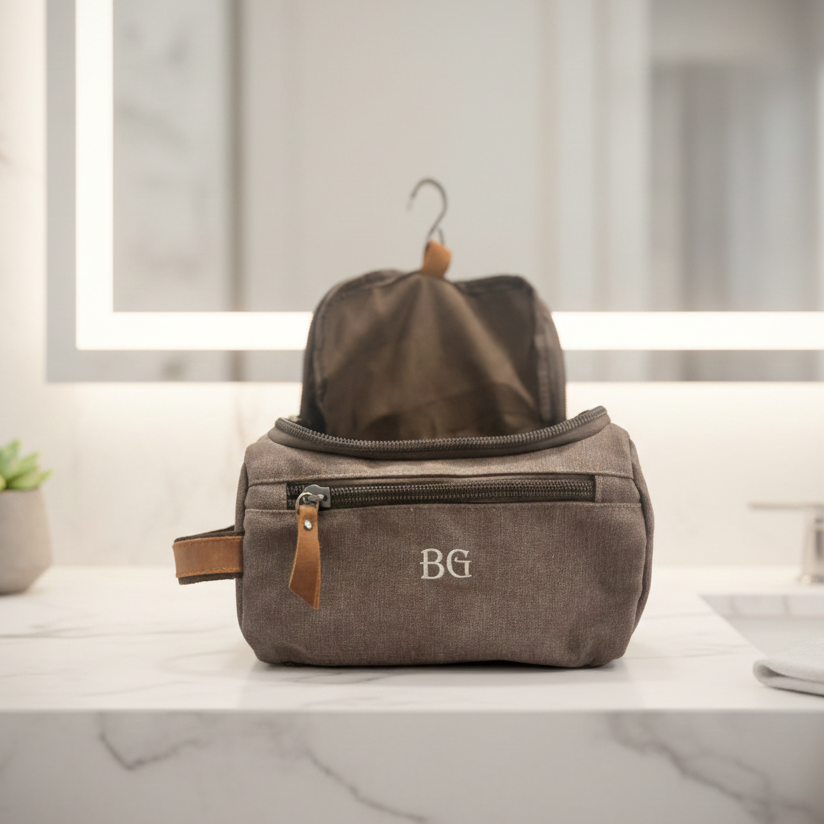 Grey toiletry bag with 'BG' monogram on a bathroom counter