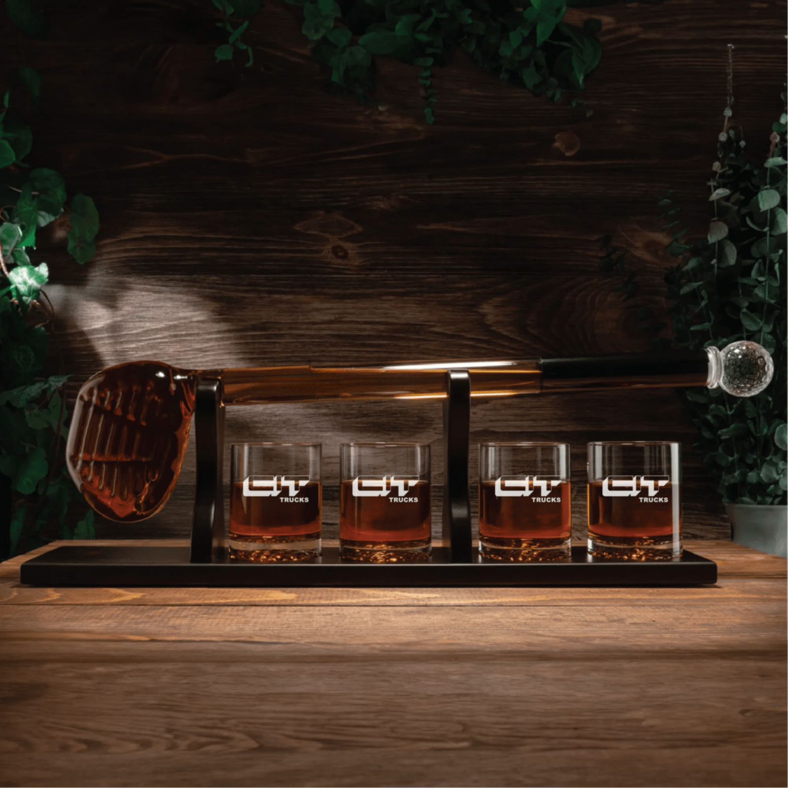 Golf club-shaped decanter with four rocks glasses engraved with sample "LIT TRUCKS" logo on black wooden stand with brass rod and glass sphere finial