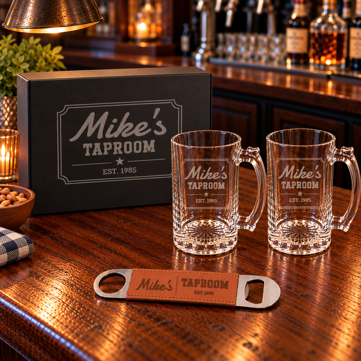 Personalized beer mug gift set on a bar: black gift box lid engraved Mike's Taproom Est. 1985, two etched glass beer mugs and a leather bottle opener
