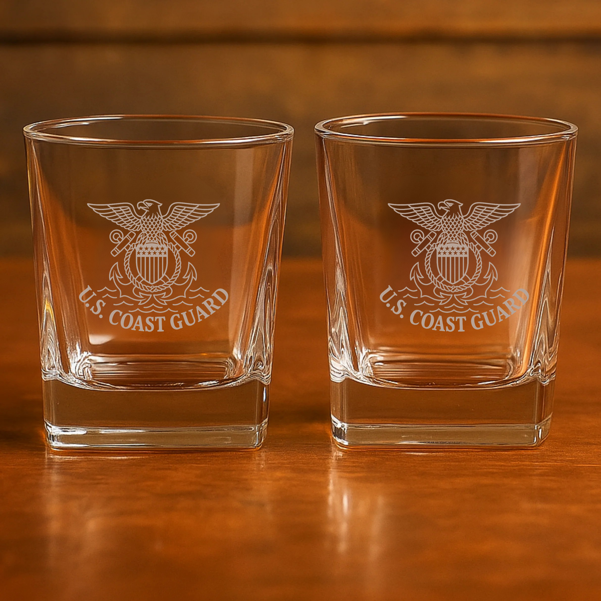 Pair of rocks glasses laser-engraved with U.S. Coast Guard eagle and shield emblem, displayed on wooden surface