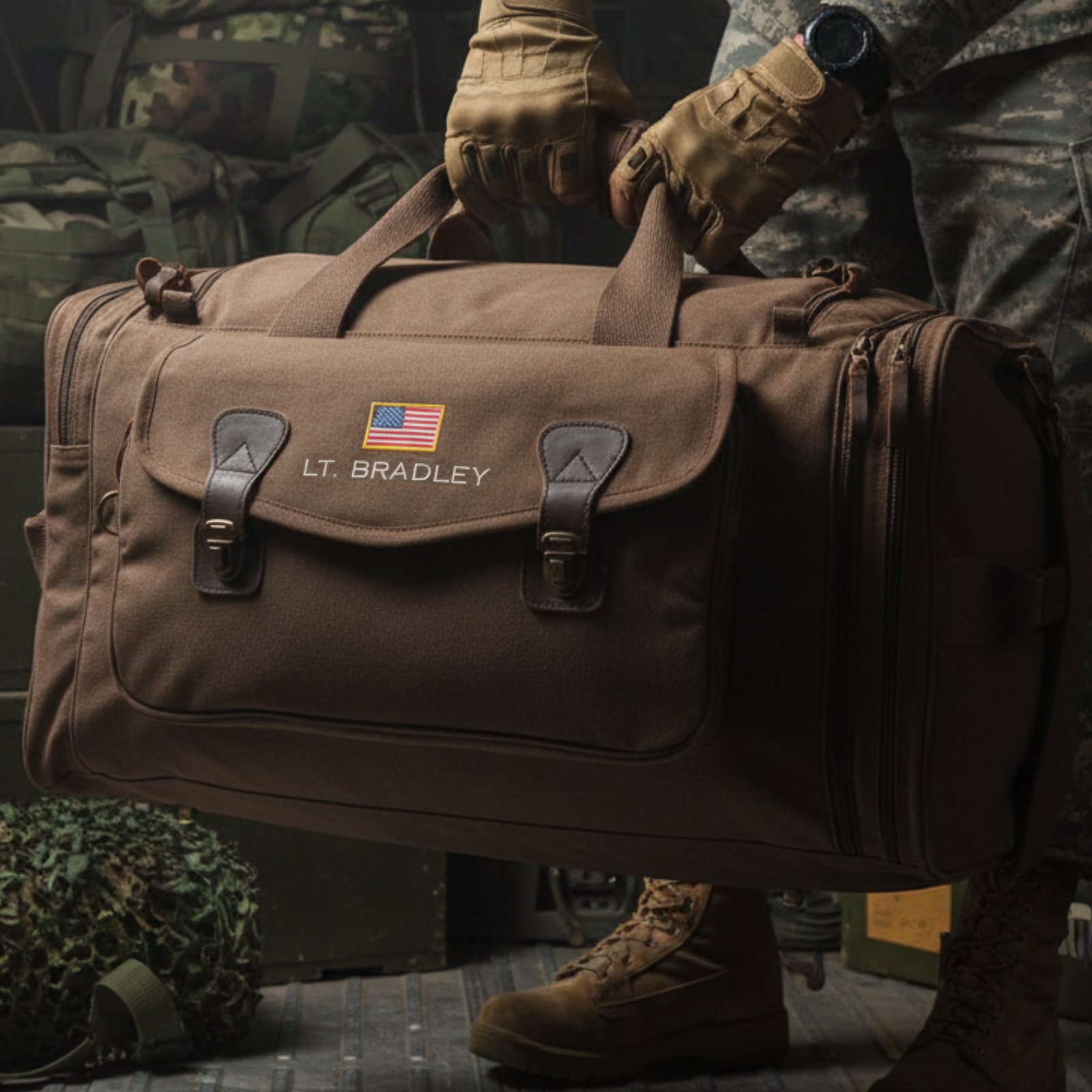 Tan canvas duffle bag with embroidered American flag and "LT. BRADLEY" sample personalization, leather handles and brass buckles, held by person in tactical gear.