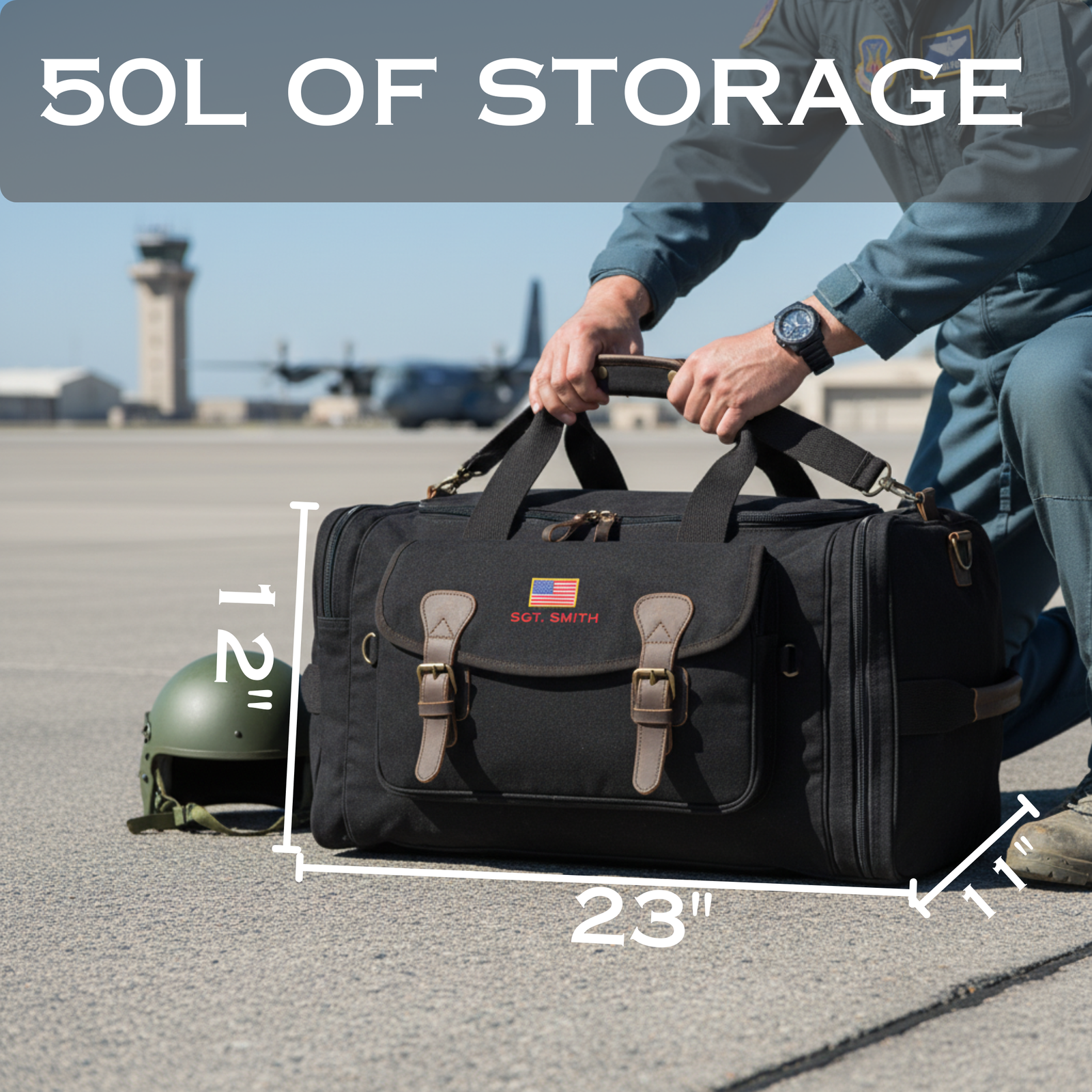 Black canvas duffle bag with leather handles and brass hardware, personalized with sample name "SGT. SMITH" and American flag, shown being held at an airfield with dimensions marked as 23 inches wide by 12 inches tall