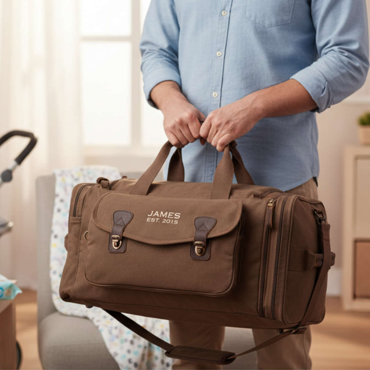 Brown canvas duffle personalized with sample embroidery reading "JAMES EST. 2015" and leather trim, held by man in light blue shirt