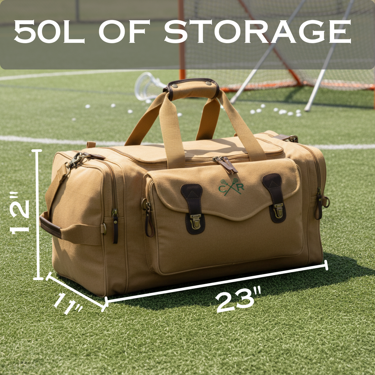 Tan canvas duffle bag with monogrammed initials displayed on synthetic grass with dimension measurements showing 23 inches wide, 12 inches tall, and 11 inches deep storage capacity