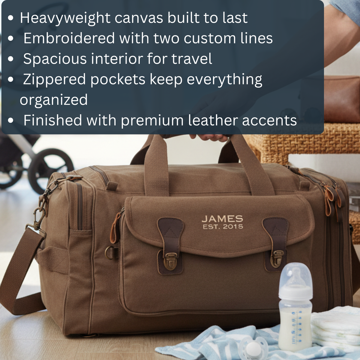 Brown canvas duffle bag embroidered with sample personalization "JAMES EST. 2015" and leather accents, displayed with baby items including bottle and diapers