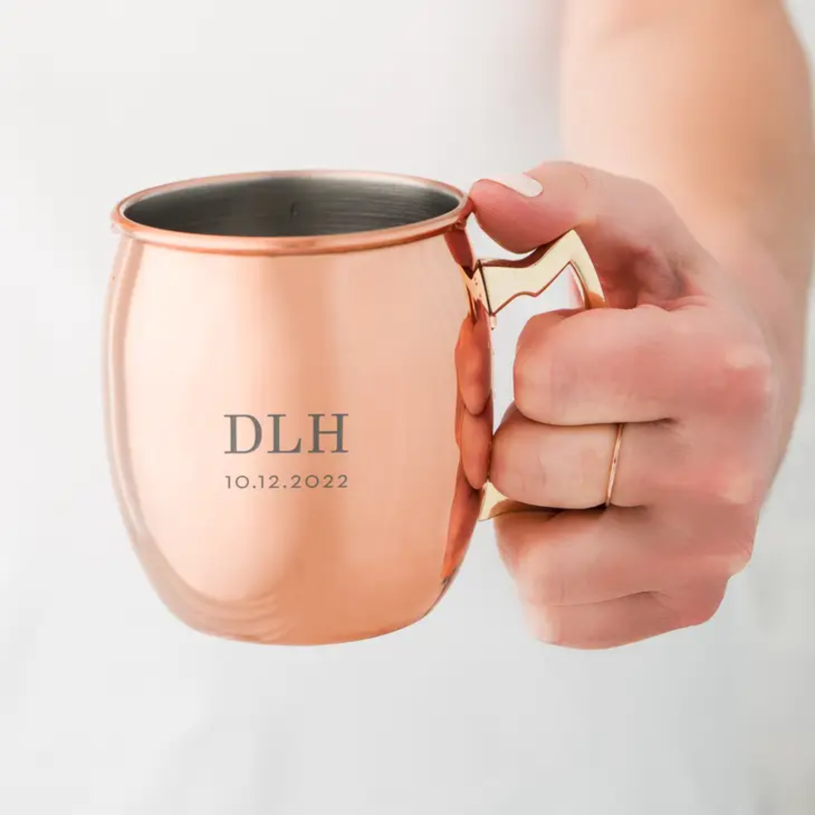 Hand holding copper Moscow Mule mug with sample engraving reading "DLH" and date "10.12.2022