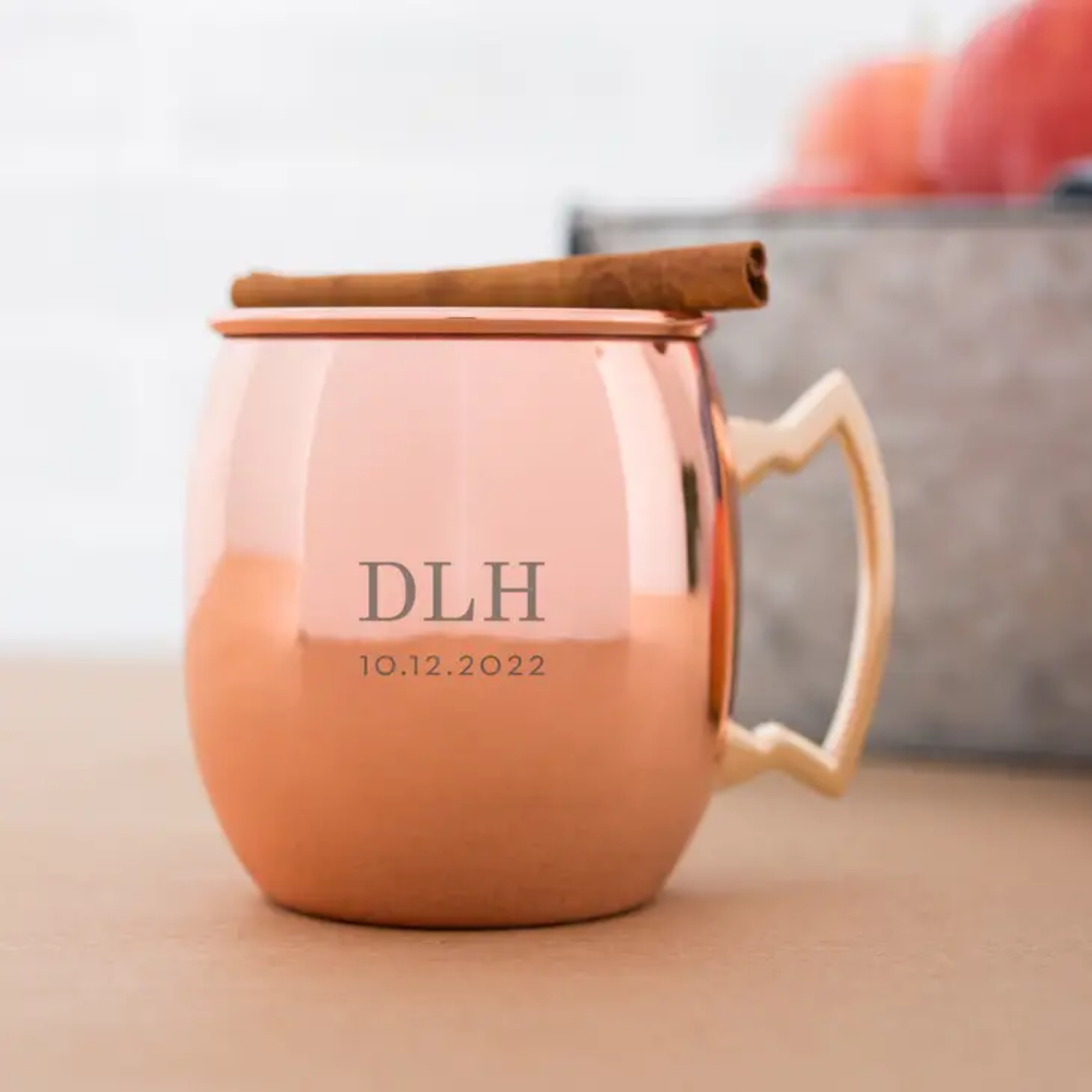 Copper Moscow Mule mug with sample engraving reading "DLH" and "10.12.2022", topped with a cinnamon stick