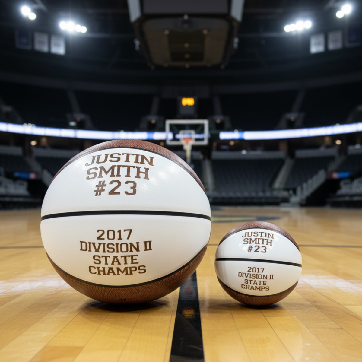 Full-size and mini personalized basketballs displayed on court, engraved with sample name "JUSTIN SMITH #23" and "2017 DIVISION II STATE CHAMPS