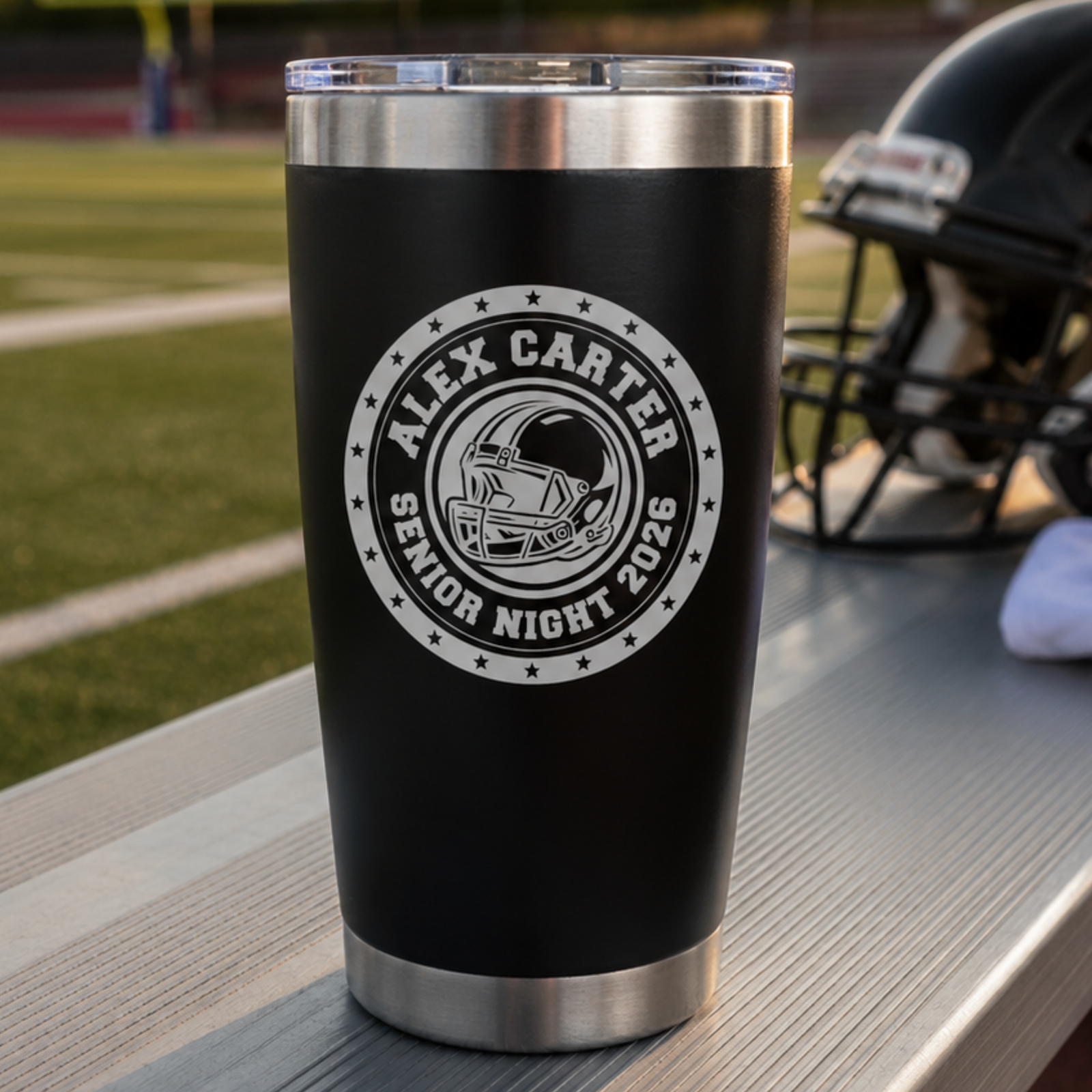 Black stainless steel tumbler with sample personalization reading "Alex Carter Senior Night 2026" and football helmet design, positioned on table near football field