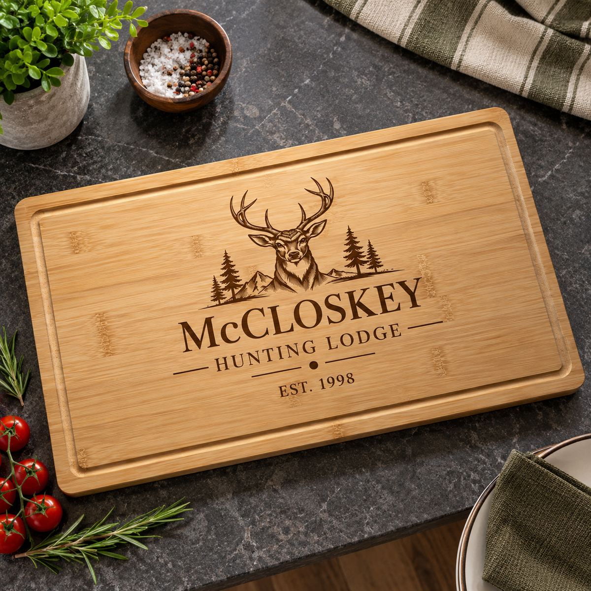 A rectangular bamboo cutting board with rounded corners, featuring a laser-engraved deer head and the text 'McCLOSKEY HUNTING LODGE EST. 1998'.