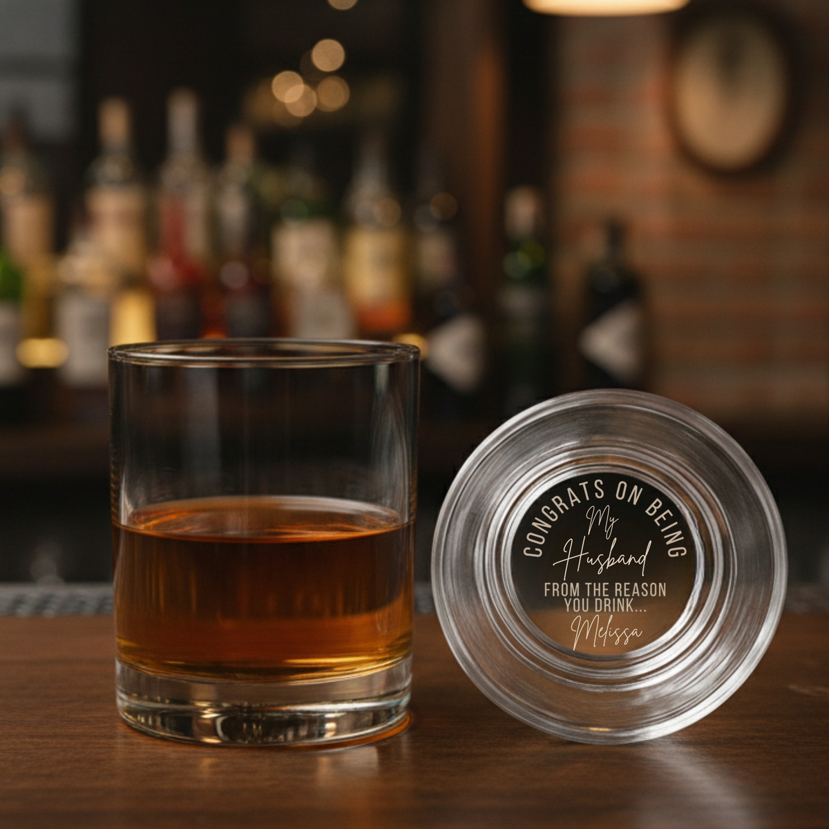 Whiskey glass with personalized laser-etched message on bottom reading "Congrats on Being my Husband From the Reason you Drink... Melissa" shown with matching coaster
