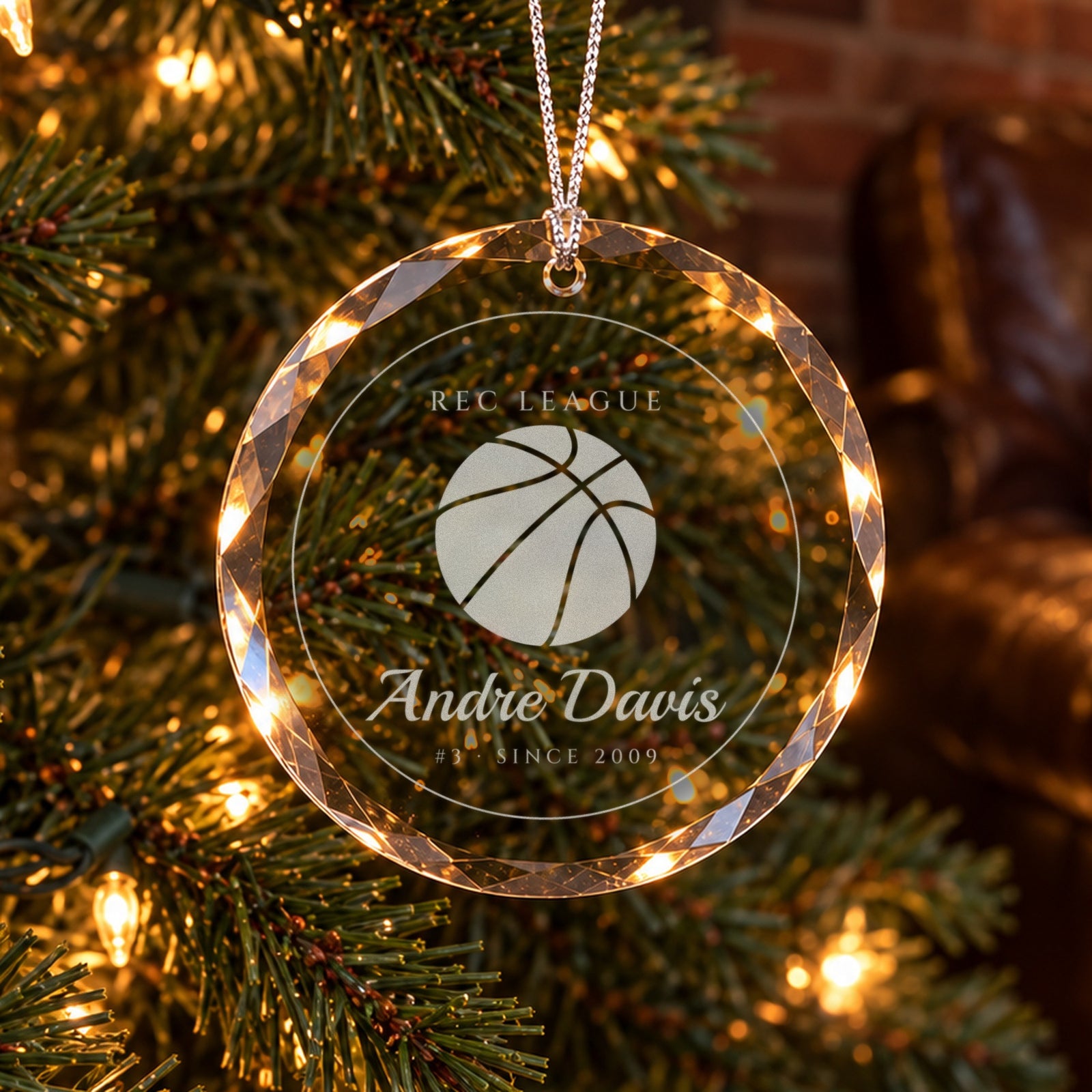Personalized basketball Christmas ornament in faceted glass on a tree in a brick-walled den, engraved with a basketball, REC LEAGUE, Andre Davis, #3 · SINCE 2009