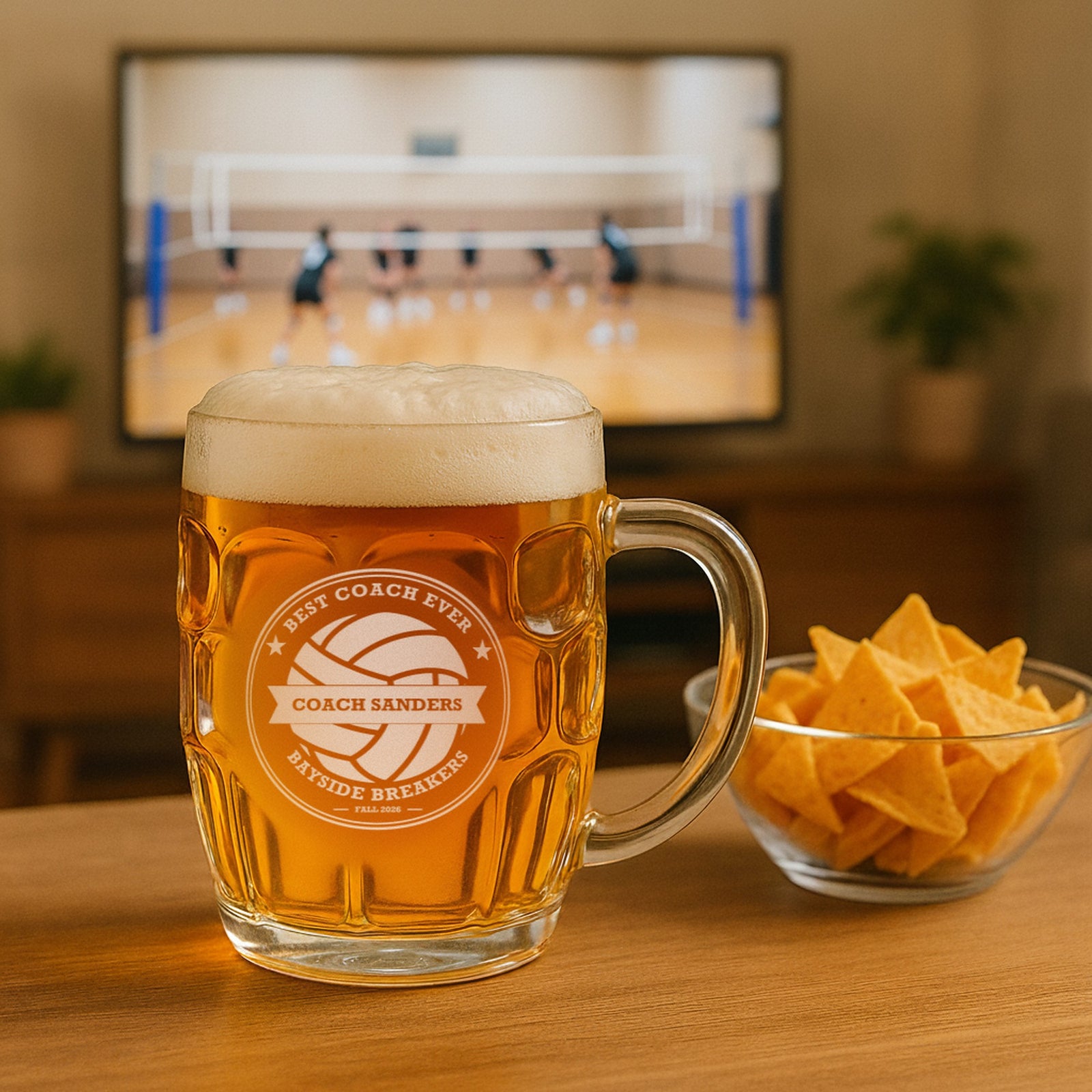 Volleyball coach beer stein engraved Best Coach Ever for Coach Sanders of Bayside Breakers, on a table with a volleyball match on TV
